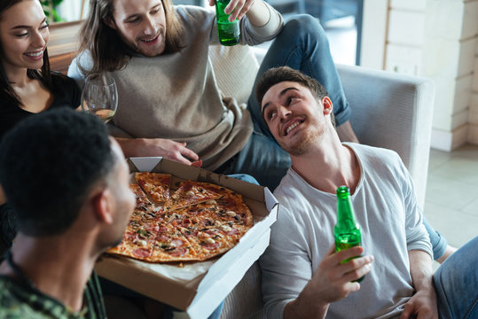 Cropped image of four friends sitting with pizza