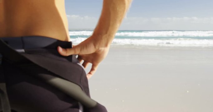 Rear view of male surfer standing in the beach