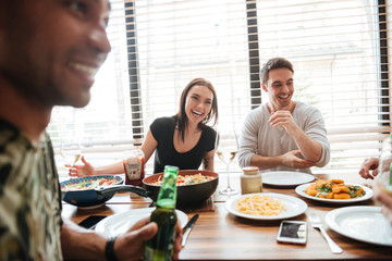 Multiracial young friends enjoying meal while sitting at the dinning table