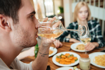 Man having dinner and drinking wine with friends on kitchen