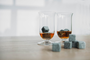 Stones for cooling whiskey and glases tulup on light wooden background