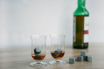 Stones for cooling whiskey and glases tulup on light wooden background