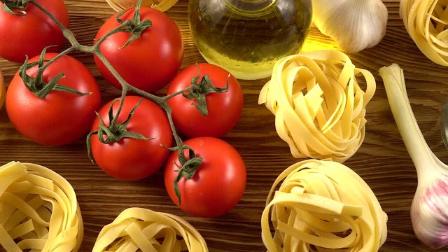 pasta, oil, tomatos and garlic on wooden background