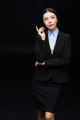 brunette pensive businesswoman in black suit  isolated on black