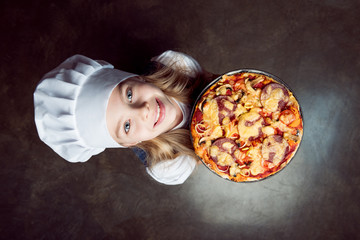 elevated view of little girl holding pizza and looking at camera