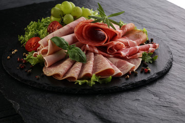 Food tray with delicious salami, pieces of sliced ham, sausage, tomatoes, salad and vegetable - Meat platter with selection