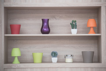 Decorative vases and lamps on wooden shelf 