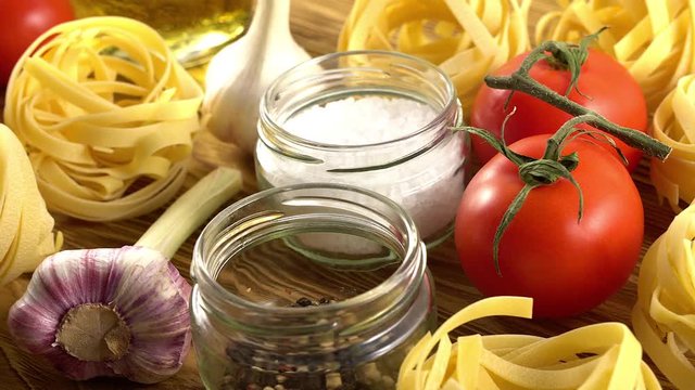 pasta, oil, tomatos and garlic on wooden background