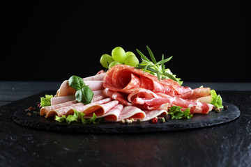 Food tray with delicious salami, pieces of sliced ham, sausage, tomatoes, salad and vegetable - Meat platter with selection