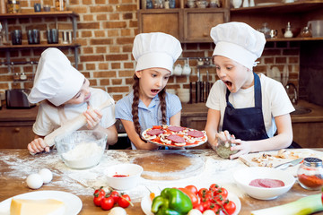kids in chef hats making pizza together
