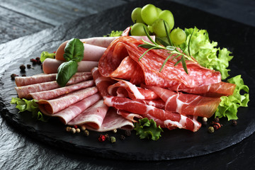 Food tray with delicious salami, pieces of sliced ham, sausage, tomatoes, salad and vegetable - Meat platter with selection