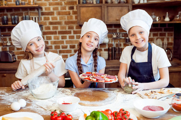 kids in chef hats making pizza together