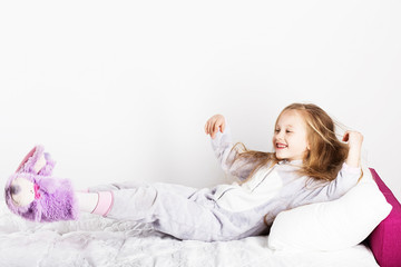 Funny little girl in pajamas jumping and having fun in bed at home. © nata_zhekova