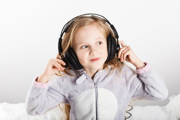 Adorable little girl in headphones enjoy with a music.
