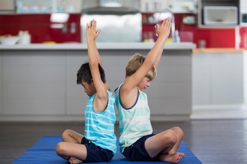 Fototapeta na wymiar Siblings performing yoga at home