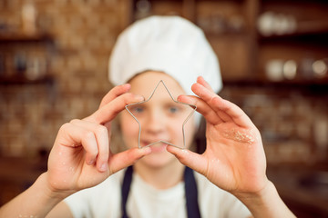 Fototapeta premium boy in chef hat holding star shaped cookie cutter