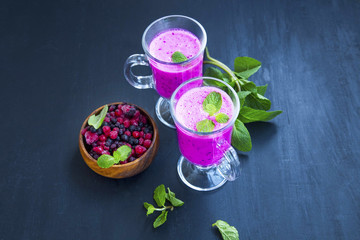 Berry smoothies in glasses with fresh mint leaves and berries bowl