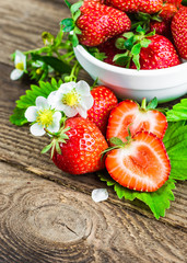 Fresh strawberries in a bowl on wooden table.
