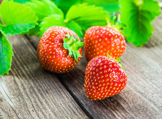 Fresh strawberries in a bowl on wooden table.
