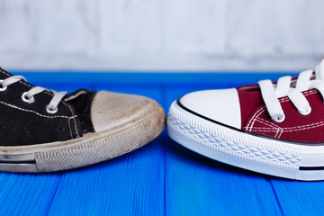 Old dirty shabby and new unworn sneakers close-up on color background, free space for advertisement or text