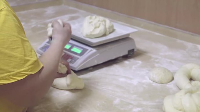 Baker cuts dough to portion and weighs raw pieces HD video. Bakery bread production, female working preparation process