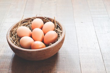 Close-up of raw chicken eggs in wooden bowl on wood background