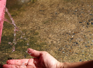 Water leaking from damaged  broken plastic bucket that make the water leak on to the man hand. 