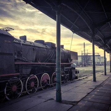 piękny parow&oacute;z stojący na stacji na tle zachodu słońca
