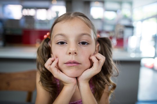 Upset girl looking at camera in kitchen