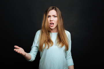 Fototapeta premium Emotional young woman demonstrating dissatisfaction in the studio