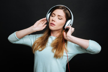 Satisfied young woman enjoying music in the studio