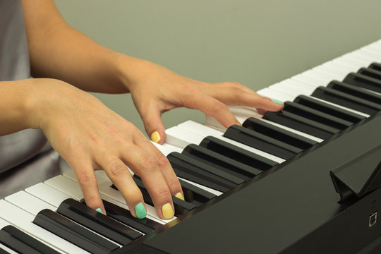 Fingers playing electronic piano keyboards