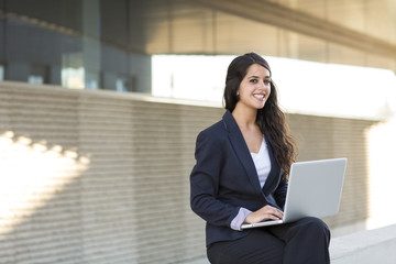 Portrait of a bussines woman working with laptop. She is wearing a black suit.