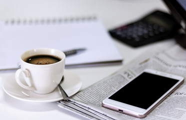 cup of coffee with Newspaper and smartphone on white table.