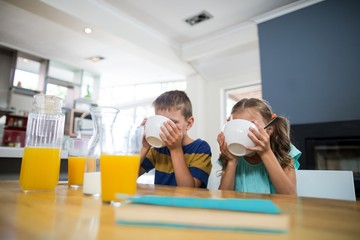 Sibling having breakfast cereal in kitchen