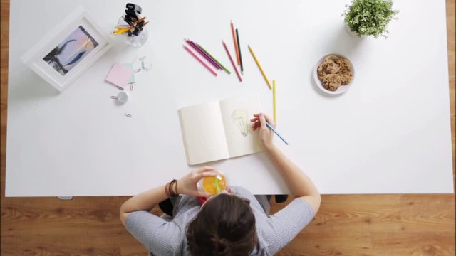 woman drawing picture in notebook at home desk