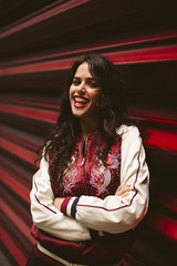 Portrait of woman in a red background, urban style, make up, fashion accessories. She is wearing a...