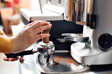 small business, people and service concept - woman or waiter in apron with holder and tamper preparing coffee at coffee shop