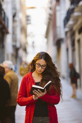 Portrait of a beautiful woman reading a book on the middle of the street.