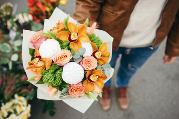Original unusual edible bouquet of marshmallow and fresh orchids, roses. Close up. Selective focus. Flower delivery. Bunch of flowers in men's hand