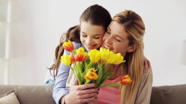 happy girl giving flowers to mother at home