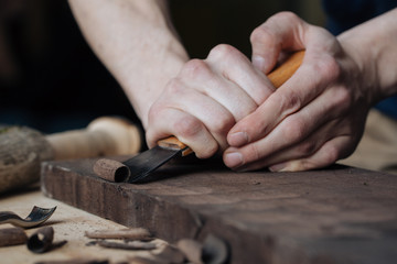 Wood carving, the master's hands work with a wooden surface, a professional does wood crafts