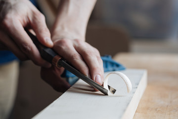 Wood carving, the master's hands work with a wooden surface, a professional does wood crafts