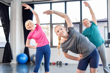 Fototapeta na wymiar Happy old couple and girl exercising in fitness class for kids and senior people