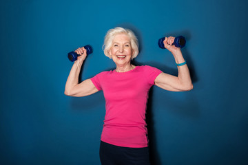 senior fitness woman training with dumbbells isolated on blue
