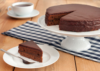 Slice of chocolate cake with a cup of tea served on a table