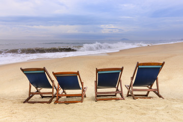 beach chairs on the sandy beaches for tourists to sit and relax with soft ocean waves breaking on beach in the early morning