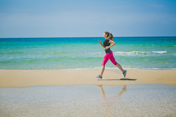 Fototapeta na wymiar Running woman. Female runner jogging during outdoor workout on beach. Beautiful fit mixed race Fitness model outdoors.