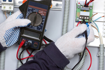 Электрик измеряет параметры электрической энергии прибором