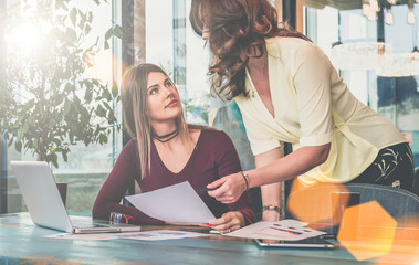 Obraz premium Two young businesswomen are discussing business plan.Girl holding documents.